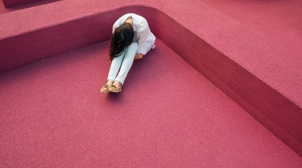 Kvinde på rødt gulv lider på grund af kronisk smerte