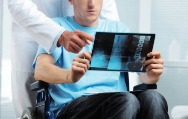 Person i kørestol med multipel sklerose ser på røntgenbillede