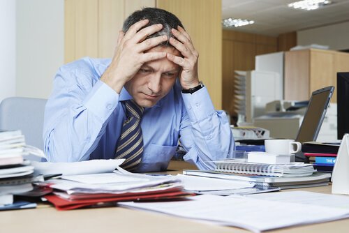 Mand på kontor tager sig til hoved som resultat af psykisk udmattelse