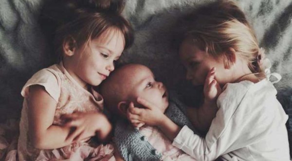 Ældre søskende krammer baby