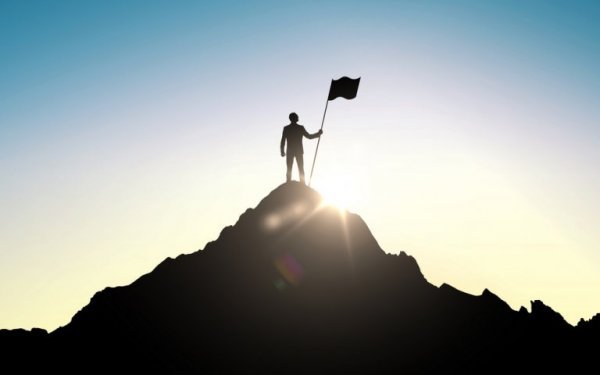 Person på toppen af bjerg med flag
