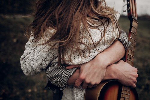 Mand med guitar krammer kvinde