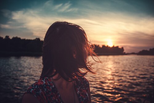 kvinder kigger bagud på soldnedgang i en flod. farvel.