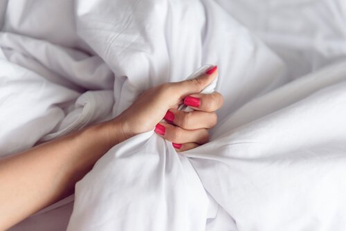 Kvindes hånd i seng under sprøjteorgasme