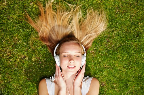 Kvinde på græs nyder effekten af musik