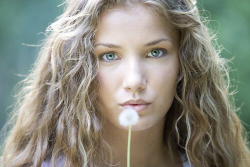 Kvinde puster til mælkebøtte