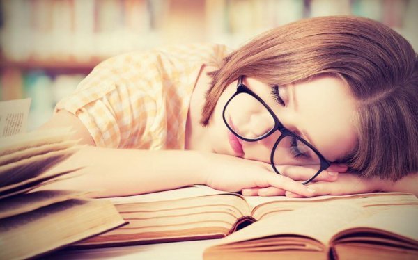 Kvinde ligger ovenpå bøger, da hun ikke kan modstå behov for at sove