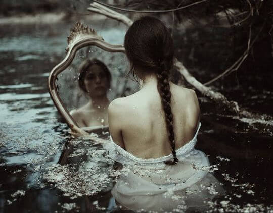Kvinde i flod ser sig selv i spejl
