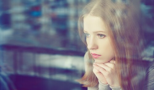 Kvinde, der mangler selvkontrol, kigger trist ud af vindue