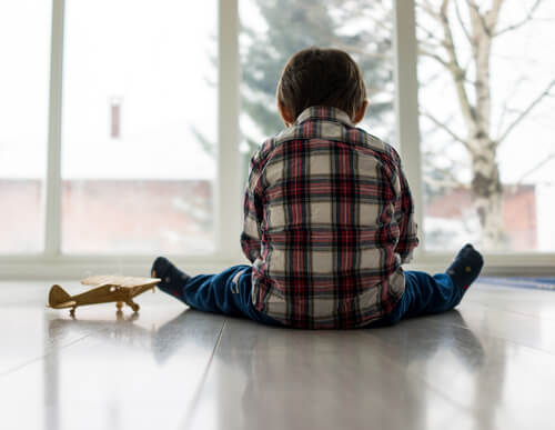 Dreng med autsime sidder alene på gulv