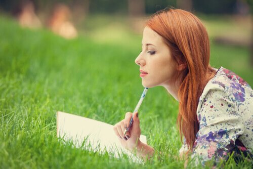 Kvinde ligger i græs og fører dagbog over påtrængende tanker