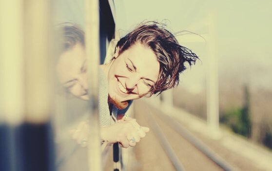 Smilende kvinde i tog nyder at rejse alene