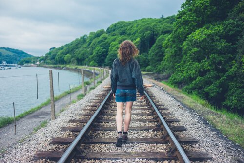 Kvinde går på togskinner og satser på, at hun ikke går glip af noget i livet