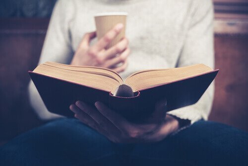 Person med kaffekop læser selvhjælpsbøger