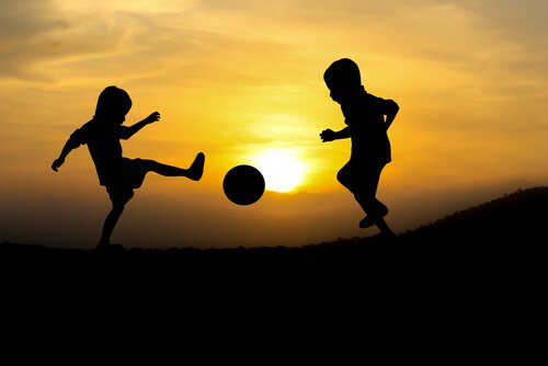 Børn spiller bold foran sol