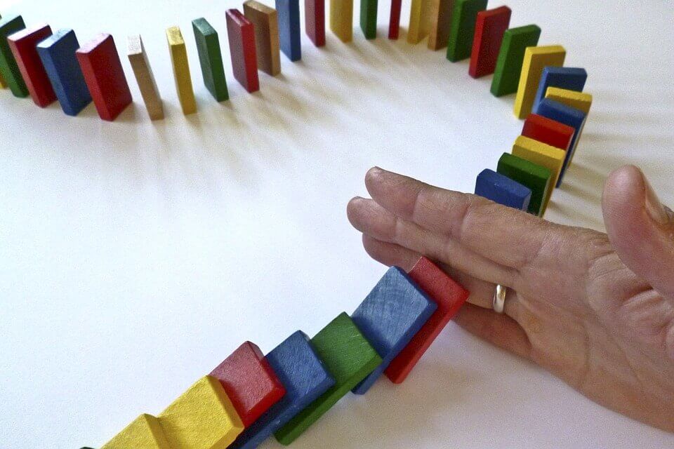 Person sætter hånd ned mellem dominobrikker