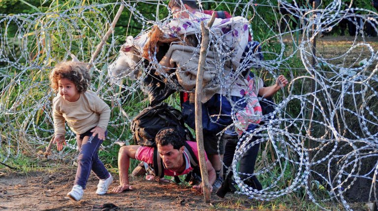 Far og barn er flygtninge og kravler gennem hegn