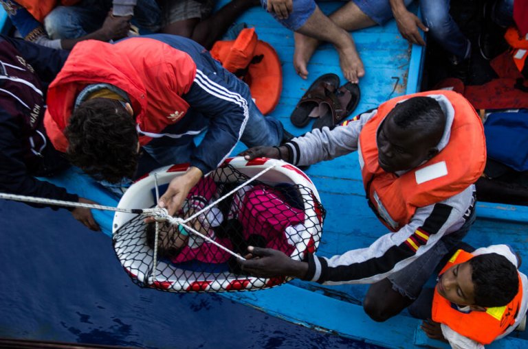 flygtningebarn hjælpes over på båd