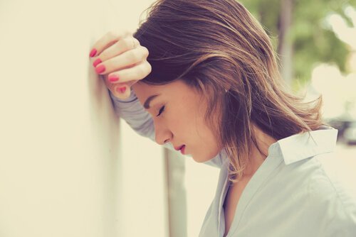 Kvinde hviler hoved på væg som følge af følelsesmæssig udmattelse