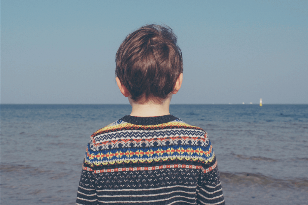 Dreng står og ser ud over hav