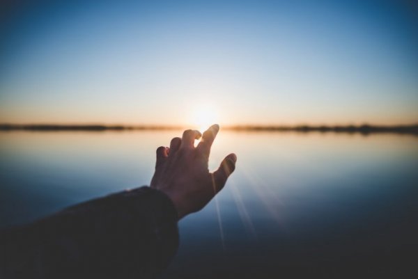 En hånd rækker ud over vand for at genvinde positiv energi