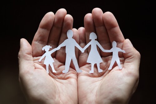 Hænder bærer familie af papirsklip som symbol for systemisk terapi