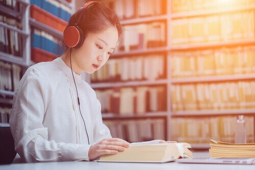 Kvinde lytter til musik, mens hun læser