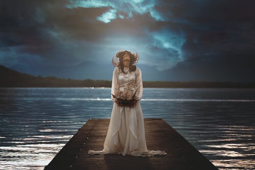 Kvinde står på bro ved sø om natten
