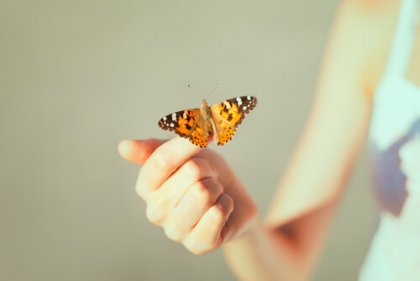 Kvinde med sommerfugl på finger