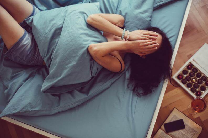 Kvinde i seng er frustreret over søvnmangel og dårlig koncentration