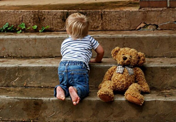 Barn på trappetrin med bamse viser babys udvikling