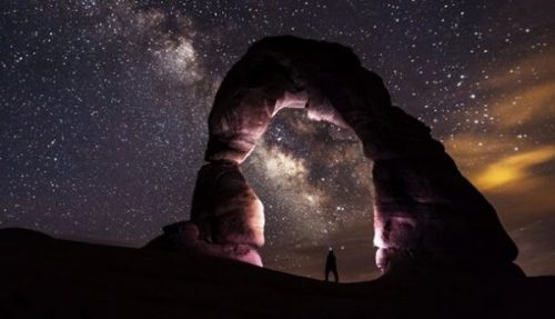 Person under stenbue kigger på stjerner