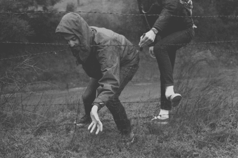 To personer kravler gennem hegn, da udfordringer kan maksimere din modstandsdygtighed