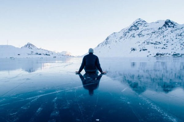 En mand sidder på is i bjergene og viser taknemmelighed