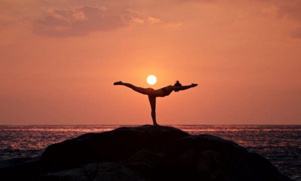 kvinde dyrker yoga ved solopgang. Motion er vigtigt