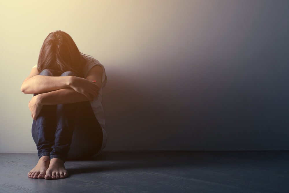 kvinde med flad affekt hviler hoved på knæ