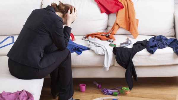 tøj på sofa og frustreret kvinde over hendes uorden.