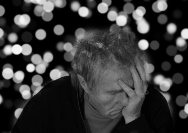 symptomerne på depression hos en ældre mand der holder sit hoved