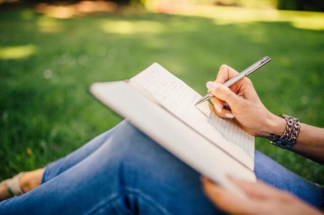 Kvinde skriver i sin journal og bruger terapeutiske skriveøvelser