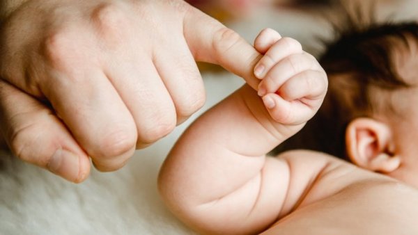 Forældre holder babyens finger for at undgå det primale sår