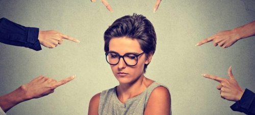 Kvinde omringet af hænder der peger finger af hende som symbol for chikane på arbejdspladsen