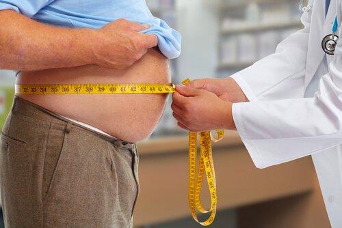Læge måler overvægtig mands mave, da fedme kan være årsag til søvnapnø