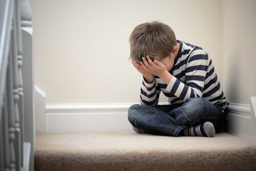 dreng der græder på gulv på grund af underminering i familien
