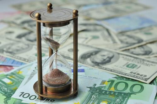 Timeglas står på en masse pengesedler. Brug dine penge på oplevelser