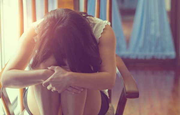 Deprimeret kvinde hviler hoved på knæ