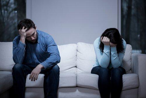 Trist par sidder i hver sin ende af sofaen og illustrerer situationen, når du skændes med din partner