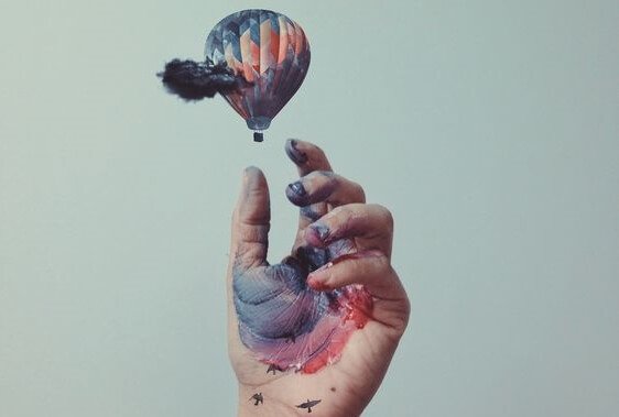 Hånd med maling griber ud mod luftballon
