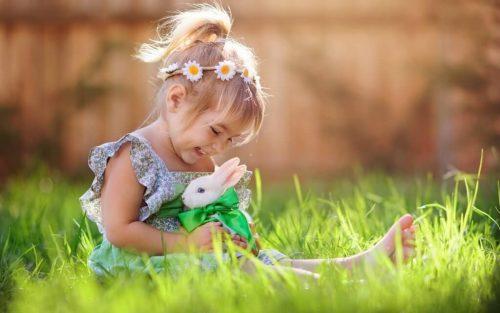 Pige sidder i græsset med kanin