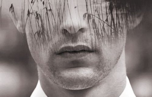 Mands ansigt i sort og hvid med siv foran