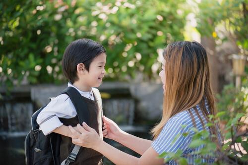Dreng med skoletaske fortæller sin mor om den bedste første skoledag